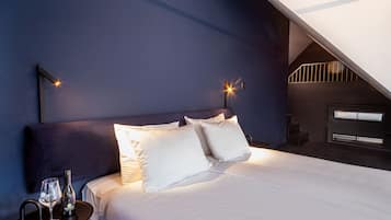 A bedroom with a bed, white bedding, a bottle of wine, and a glass on a side table.