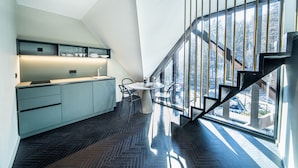 Una cocina moderna con comedor, una escalera y vistas al exterior.