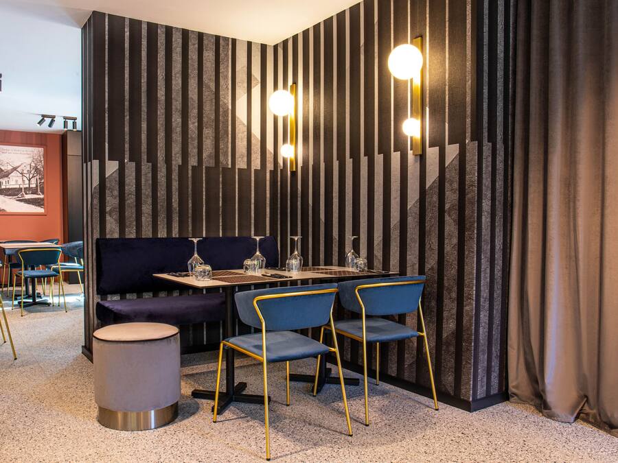 A modern dining area with a dark, textured wall, a round table with chairs, and a bench.