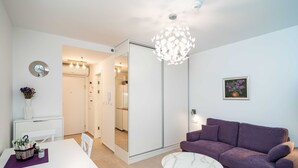 Una sala de estar moderna con una mesa blanca, un sofá púrpura y una mesa de centro de mármol.