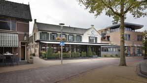 Un hotel con fachada moderna, un espacio de estar techado al aire libre y una entrada visible.