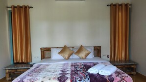 A neatly made bed with patterned bedding, a wooden headboard, and a wall-mounted air conditioner. - Homocation Sikhiri Cottages (Barnagar)