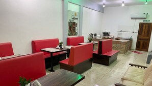 Un restaurante con asientos rojos tipo banca, una mesa de madera y un sofá.