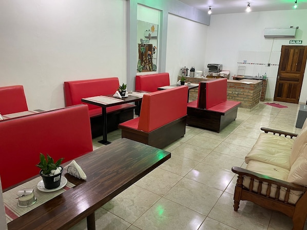 Un restaurante con asientos rojos tipo banca, una mesa de madera y un sofá.