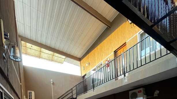 Un espacio interior amplio con suelo de baldosas, una escalera que sube a un nivel superior y un balcón con barandilla.