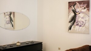 Een kamer met een zwarte dressoir, een spiegel en een schilderij van dansers aan de muur.