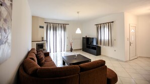 Een moderne woonkamer met een bruine zithoek, een flatscreen televisie, een open haard en een eethoek met een salontafel.