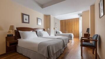 Habitación de hotel con dos camas, suelo de madera y una silla.