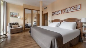 Una habitación de hotel con una cama grande, un sofá, un escritorio y un espejo.