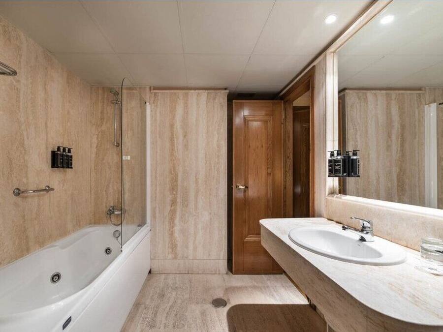 Un baño moderno con bañera, un espejo grande y un lavamanos.