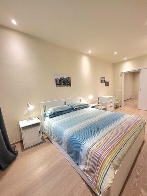 Ein Schlafzimmer mit Bett, Nachttischen, einem Kleiderschrank und einem Bild an der Wand.
