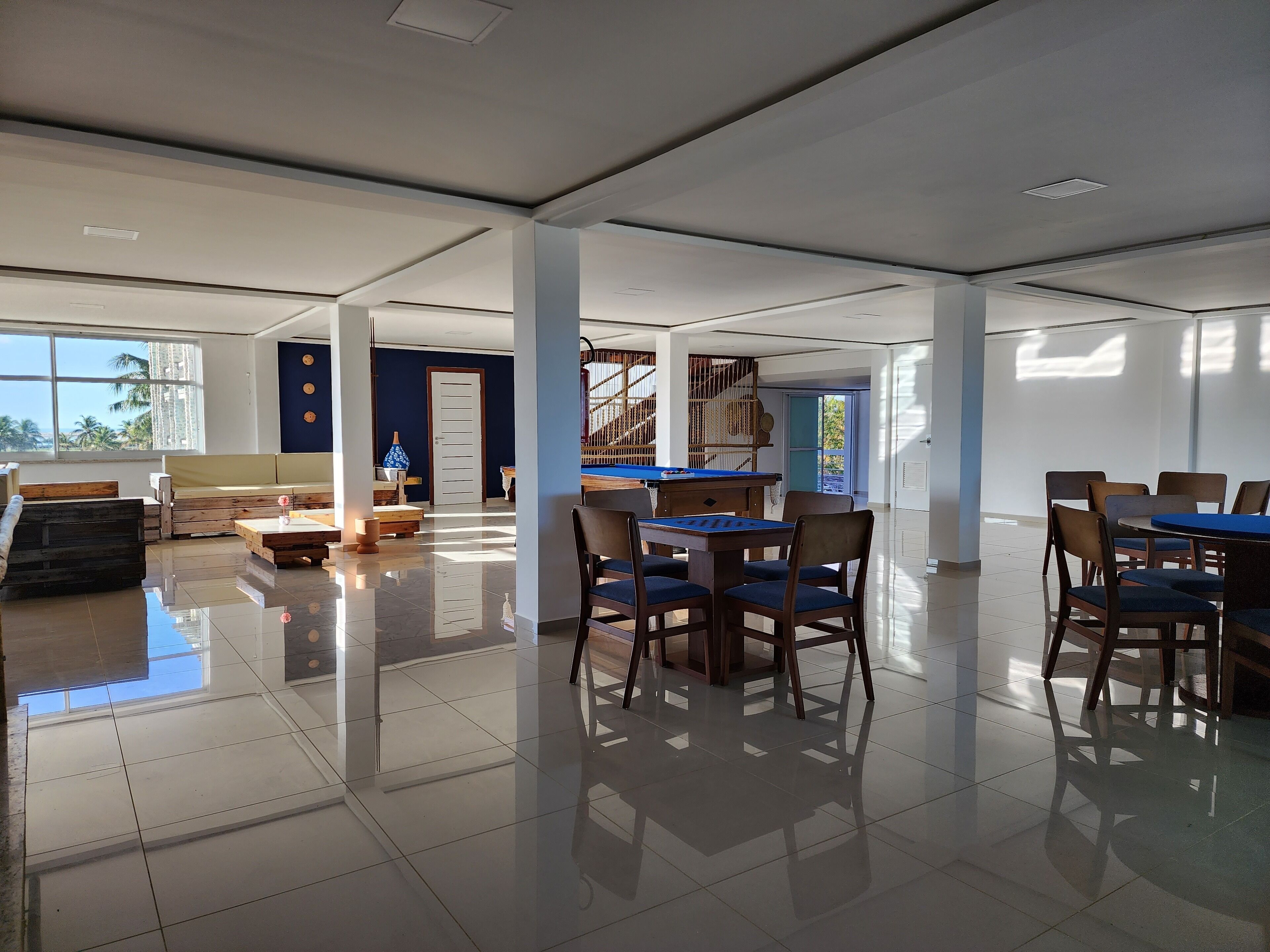 A spacious room with a pool table, a billiards table, and a dining area with chairs and a table.