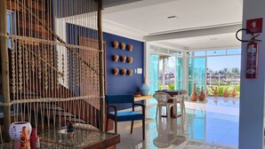 Un interior moderno con un separador de madera, una pared azul decorada y una mesa de vidrio, con vistas al exterior.
