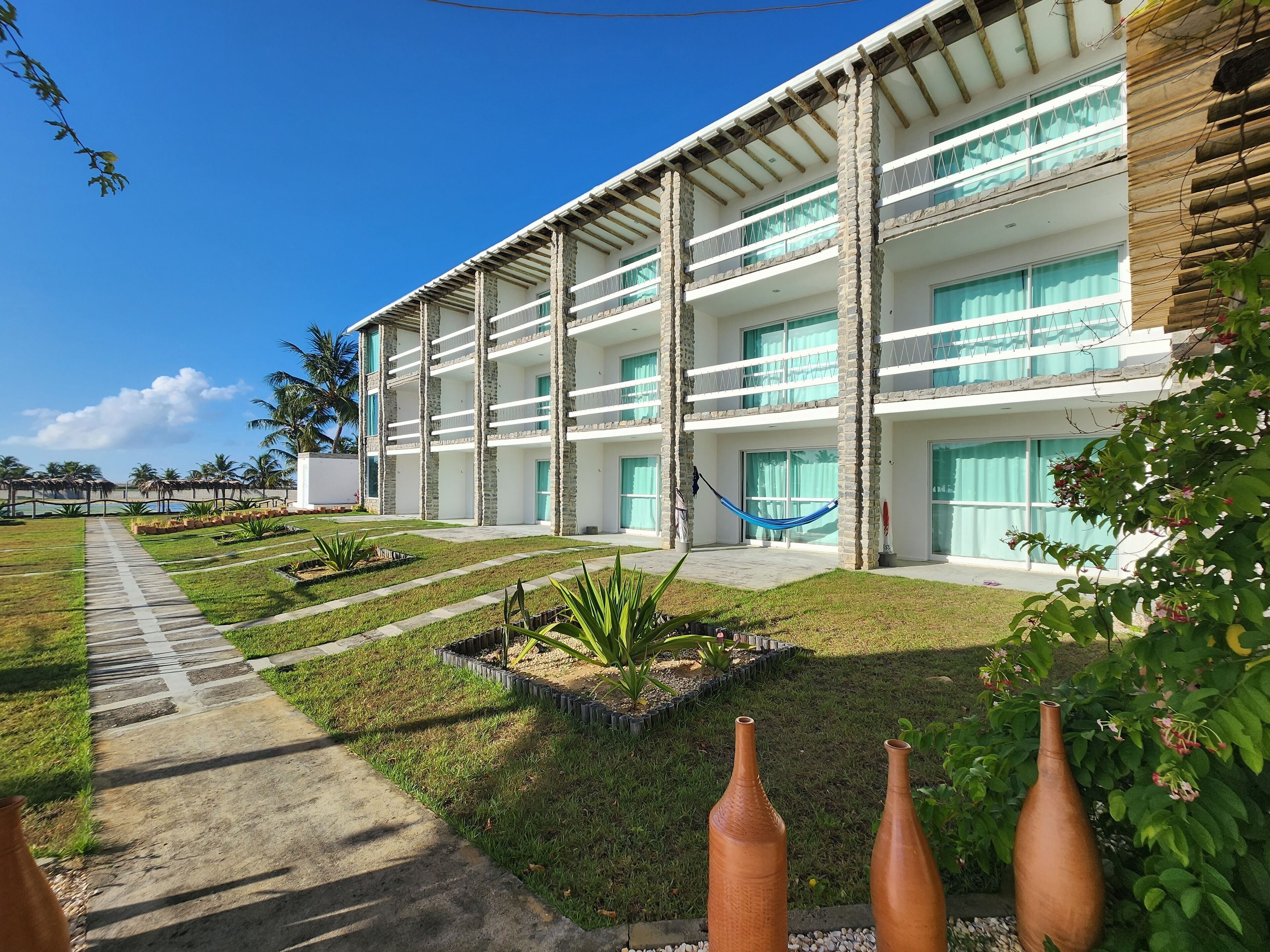 A multi-story hotel with a central courtyard, outdoor seating, and a pool.