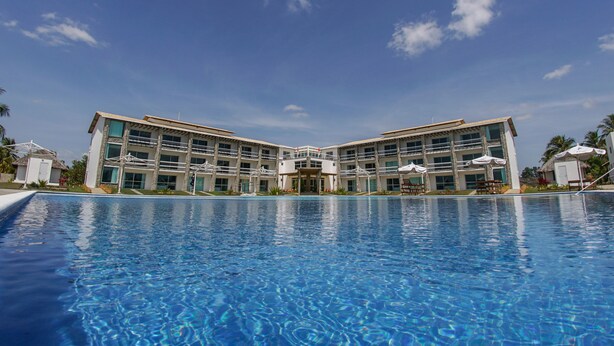Un hotel con una piscina grande, varios balcones y una entrada principal.