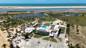 Vista aérea de un resort con piscina, cancha de tenis y acceso a la playa.