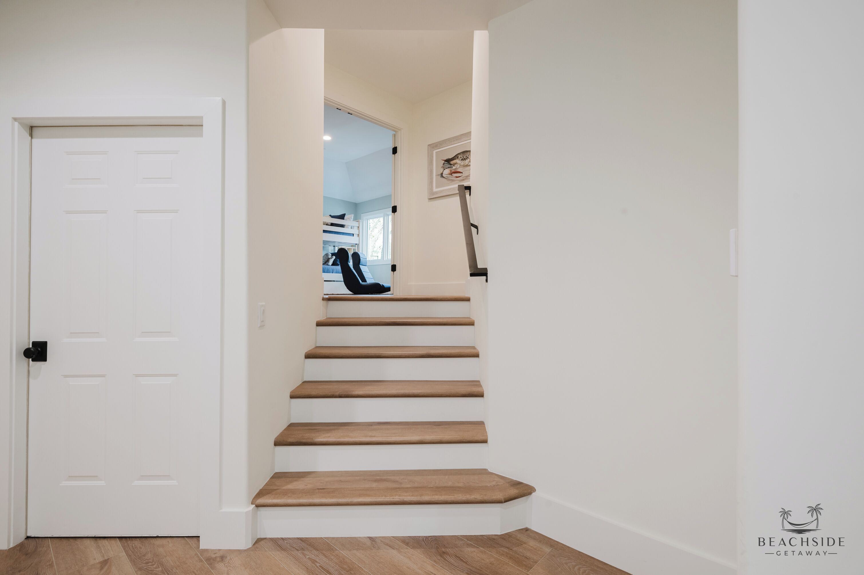 A staircase with wooden steps leading to a room with a bed and a desk.