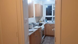 A compact kitchen with wooden cabinets, a built-in oven, and a window.