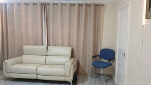 A room with a beige sofa, a blue chair, and a door with a light strip.