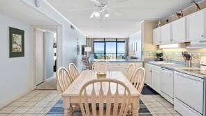 A spacious kitchen with a dining area, white cabinetry, and a view of the ocean.