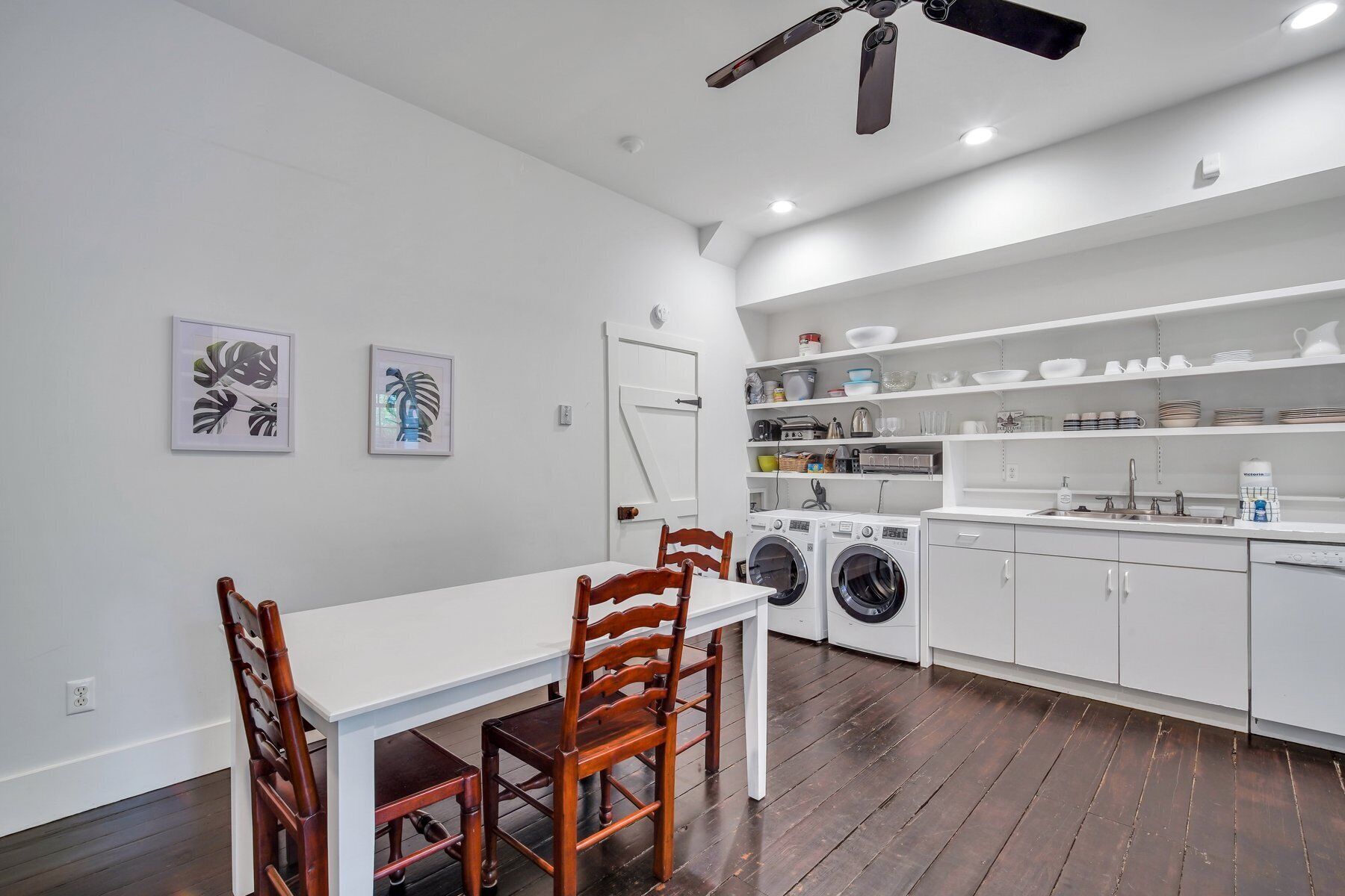 Una cucina moderna con mobili bianchi, un tavolo da pranzo con sedie e una ventola a soffitto.