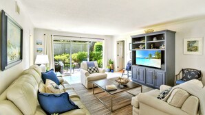 Ein Wohnzimmer mit Sofa, Sesseln, Couchtisch, Fernseher und Schrank.