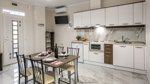 Een moderne keuken met witte kasten, een inbouwoven en een marmeren aanrecht.