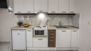 Een compacte keuken met witte kasten, een inbouwoven, een spoelbak en een kleine koelkast.