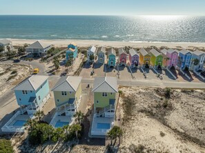 A beachfront property with colorful houses, a swimming pool, and a road leading to the beach. - Welcome to Cotton Patch! (St. George Island)
