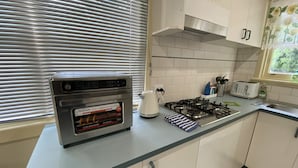 Une cuisine équipée d’un four à friture à air en acier inoxydable, d’une cuisinière à gaz, d’une bouilloire et d’un grille-pain.