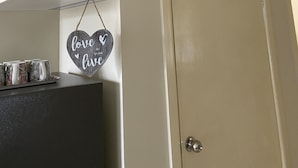 Une pièce avec une porte beige, un climatiseur blanc et une décoration en forme de cœur sur laquelle on peut lire les mots « love live », le tout étant accroché au mur.
