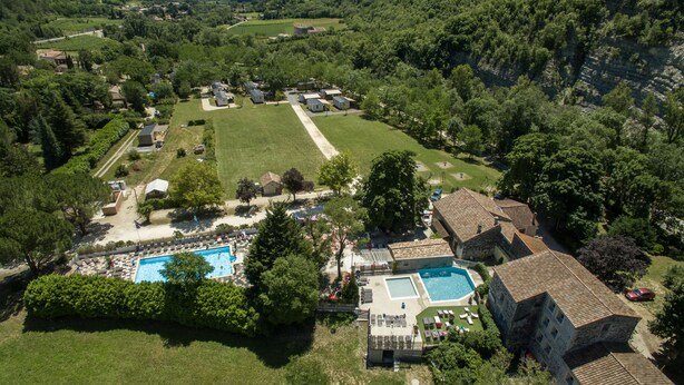 Vista aérea de un barrio residencial con varias casas, una gran piscina y un césped bien cuidado.
