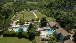 Vista aérea de um bairro residencial com várias casas, uma grande piscina e um gramado bem cuidado.