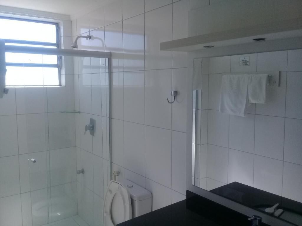 Um banheiro moderno com box de vidro, vaso sanitário e pia com espelho.