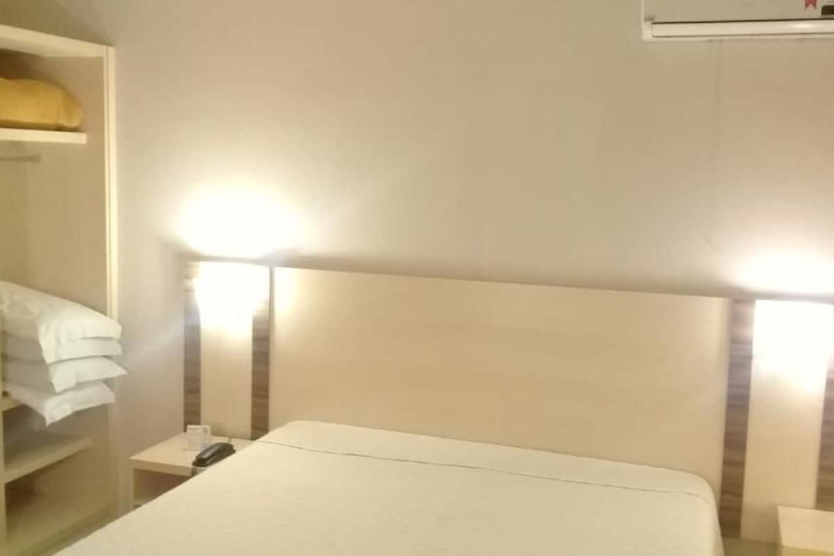 Ein Hotelzimmer mit einem Bett, Nachttischen, einem Kleiderschrank und einer Klimaanlage.