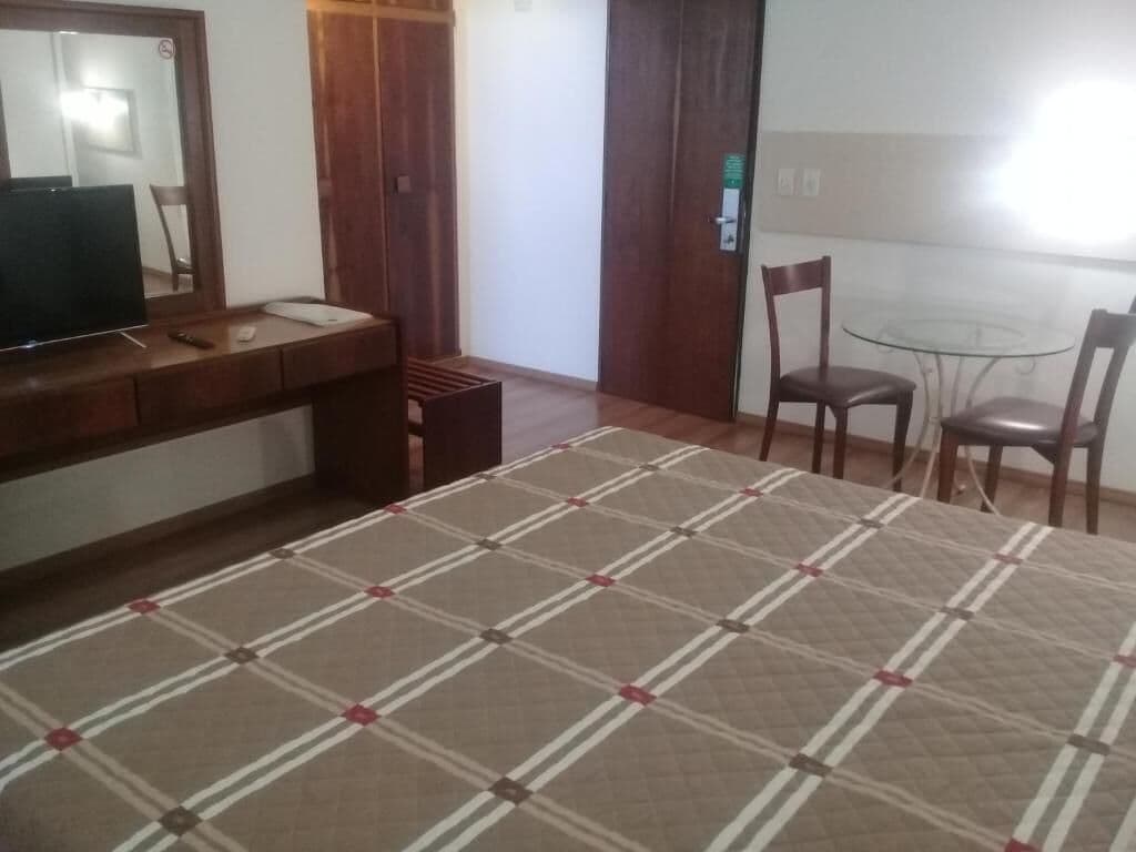 Une chambre d’hôtel avec un lit, un bureau doté d’un miroir, une chaise et une petite table.