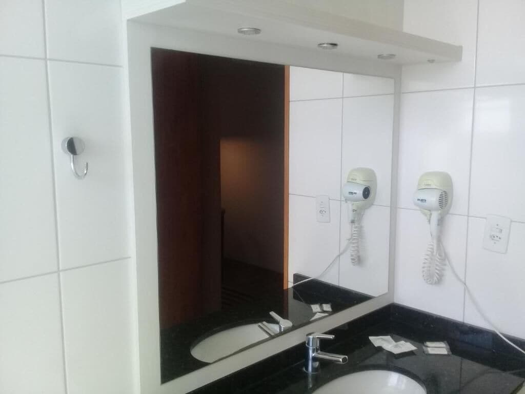 Un baño con dos lavamanos, un espejo y secadores de pelo montados en la pared.