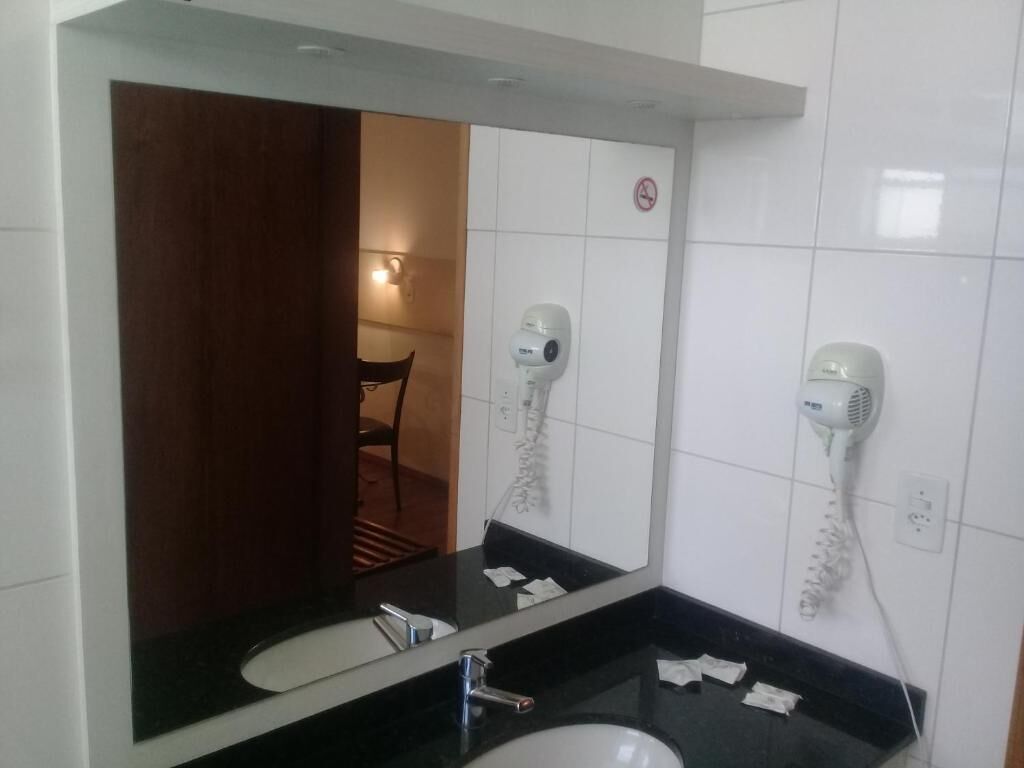 A bathroom with a large mirror, two sinks, and two hair dryers mounted on the wall.