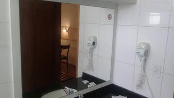 A bathroom with a large mirror, two sinks, and two hair dryers mounted on the wall.