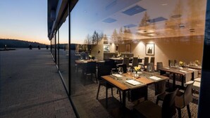 A restaurant with tables set for dining, a view of the outdoors, and a modern interior design.