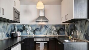 Cozinha moderna com micro-ondas embutido, forno e máquina de lavar, uma ilha grande com pia e um backsplash abstrato e original.