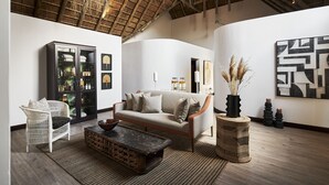 Una sala de estar con techo alto, un sofá, un sillón de mimbre, un aparador y una mesa de centro.