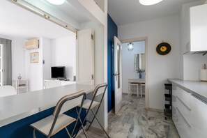 A modern kitchen with white cabinets, a marble floor, and a blue accent wall.