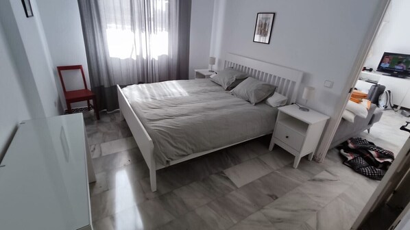 A modern bedroom with a bed, bedside tables, a TV, and a red chair. - Apartment "Ático Castillo" with Sea View, Shared Pool & Wi-Fi (Fuengirola)