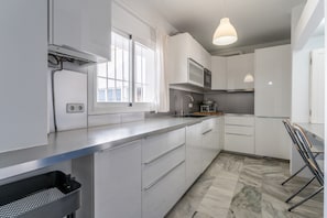 A modern kitchen with white cabinets, a stainless steel countertop, a microwave, and a sink. - Apartment "Ático Castillo" with Sea View, Shared Pool & Wi-Fi (Fuengirola)