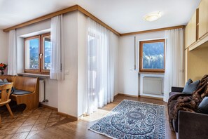A room with a wooden floor, a patterned rug, a sofa, a chair, and a table.