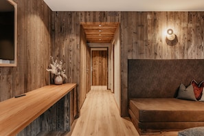 Un intérieur en bois comprenant un canapé, un banc en bois et un luminaire fixé au mur.