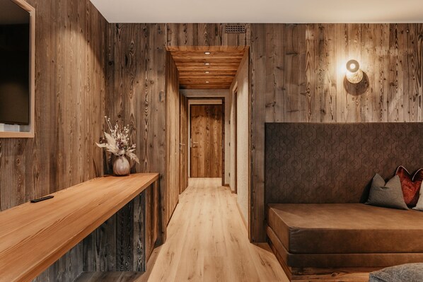 A wooden interior with a sofa, a wooden bench, and a wall-mounted light fixture.