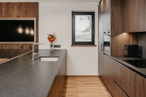 A modern kitchen with a large island, built-in oven, and a window above the sink.