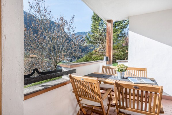 Un balcon avec une table et des chaises, donnant sur un paysage montagneux.